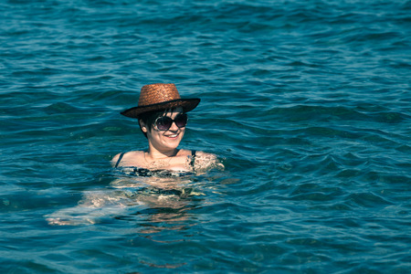 Young happy woman in hat swimming in sea.の写真素材