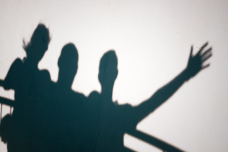 Creative photo of three people shadows on white wall gesturingの写真素材