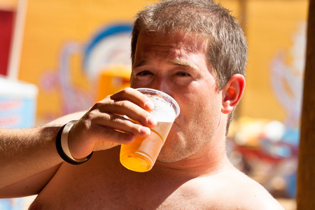 Close up of shirtless young man holding beer.の写真素材