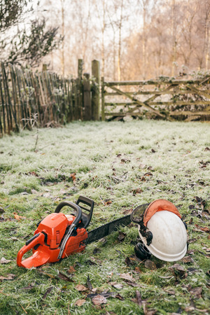 Chainsaw and helmet lying in the garden.の写真素材