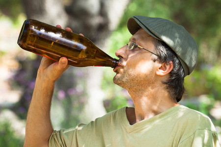Close up of a man drinking beer from bottle outdoors.の写真素材