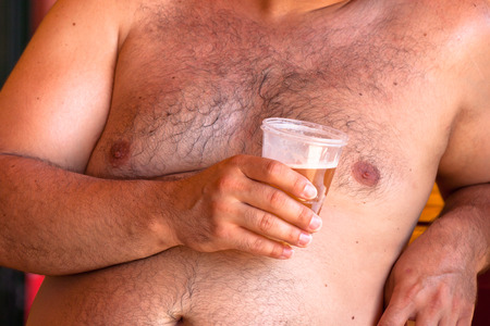 Detail of shirtless obese man holding beer.の写真素材