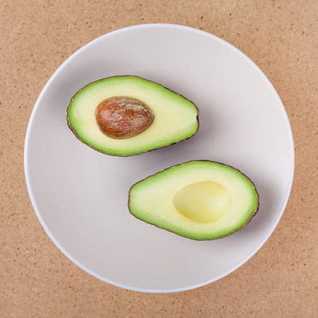 Fresh halved avocado on plate, over wooden background.の写真素材