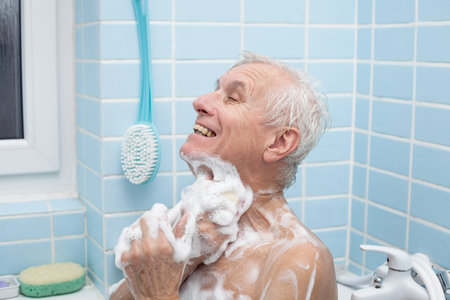 Senior man washing his body with soap in bath.の写真素材