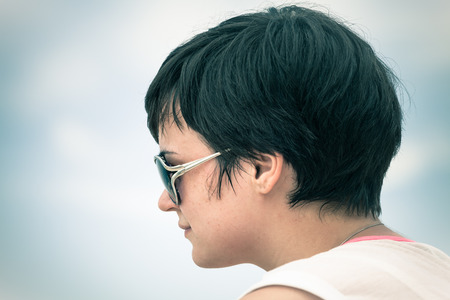 Profile of young woman face in sunglasses over sky.の写真素材