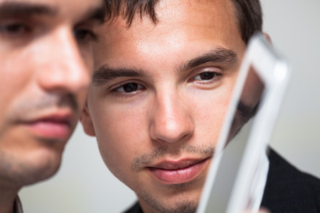 Closeup of two businessmen looking at digital tablet.の写真素材