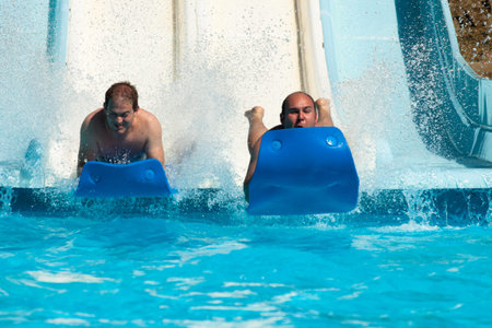 People having fun, sliding at water park.