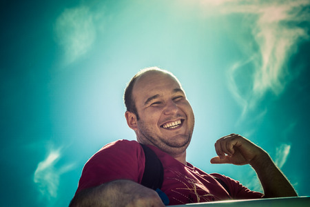 Happy man laughing over bright blue skyの写真素材