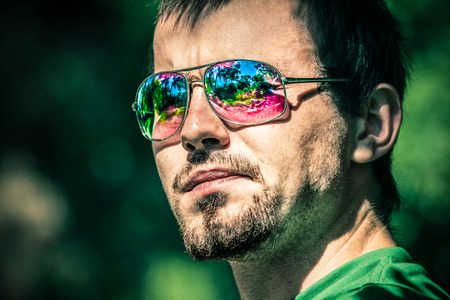 Portrait of young man wearing sunglasses with colourful reflectionの写真素材