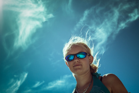 Smiling woman wearing sport sunglasses over bright blue skyの写真素材