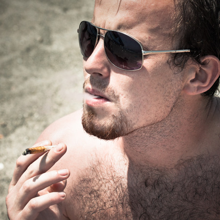 Close up of young man smoking hashish joint.の写真素材