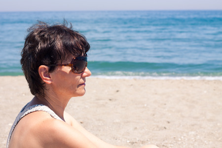 Portrait of happy middle aged woman relaxing on the beach.の写真素材