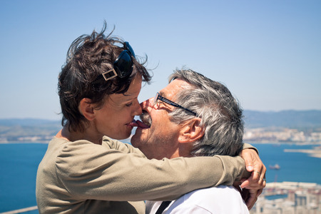 Happy middle aged woman and senior man in love kissing outdoors.の写真素材