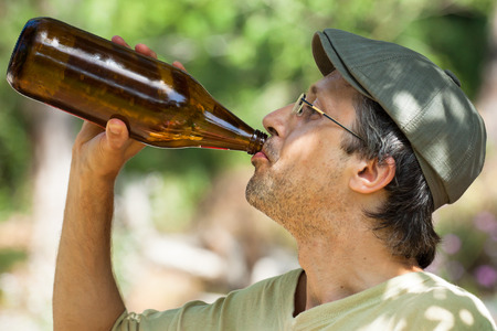 Close up of a man drinking beer from bottle outdoors.の写真素材