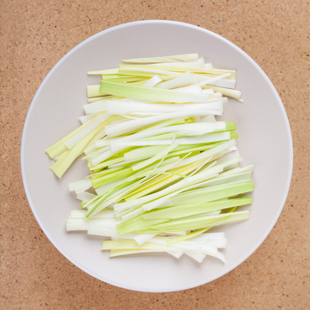 Fresh sliced leek on plate, over wooden background.の写真素材