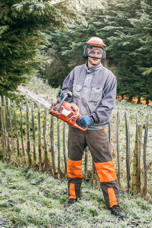 Portrait of professional gardener with chainsaw standing in the garden.の写真素材