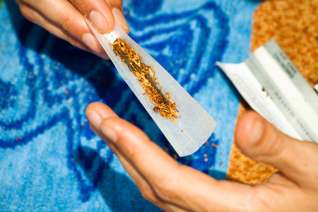 Close up of male hand rolling hashish joint.の写真素材