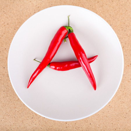 Fresh raw red hot chili peppers on plate arranged in A letter shape.の写真素材