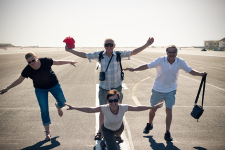 Funny group of tourist people imitating airplane at the airport runway.の写真素材
