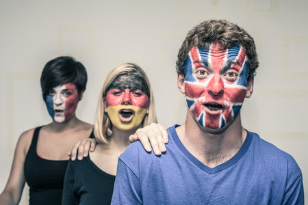 Group of excited people with painted flags on their faces shouting.の写真素材