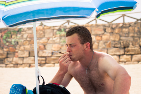 Young man smoking marihuana on the beach during summer vacation.の写真素材