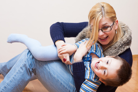Happy child boy and woman having fun at homeの写真素材