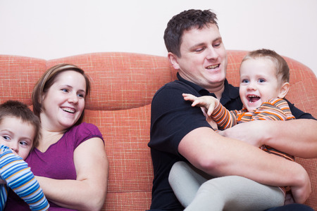 Happy parents with children having fun at homeの写真素材