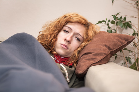 Unhappy tired redhead woman resting on the sofa at home.の写真素材