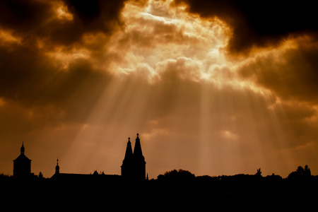 Dramatic dark sky with streaming lights and silhouette of an ancient church in the Czech Republic.の写真素材