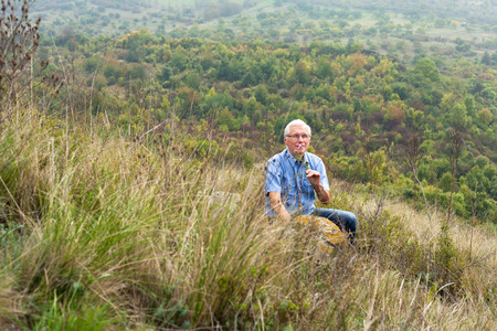 Happy senior man relaxing in the grass and enjoying green nature.の写真素材