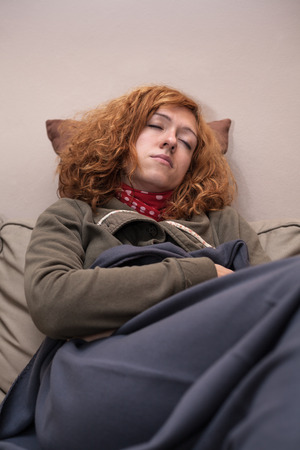 Young redhead woman sleeping on the sofa at home.の写真素材