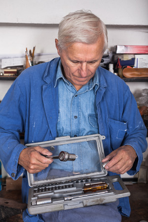 Senior worker with ratchet and tools in the workshop.の写真素材