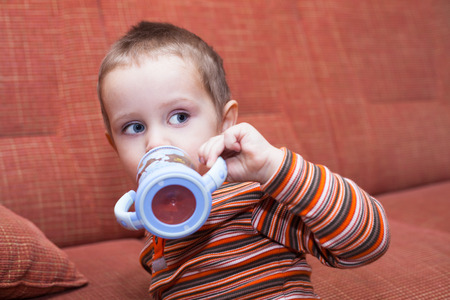 Child boy with drink bottle at homeの写真素材