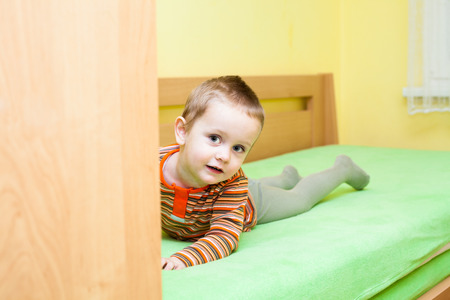 Cute child boy lying on bed at homeの写真素材