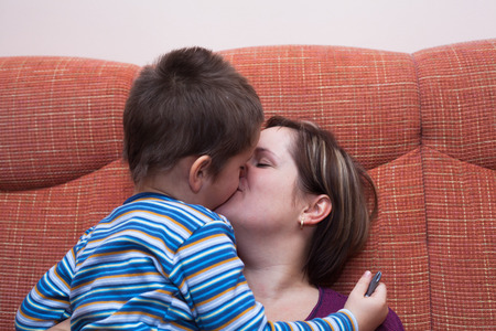 Closeup of happy mother kissing her child boyの写真素材