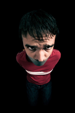 Kidnapped man hostage with tape over mouth and tied up with ropeの写真素材
