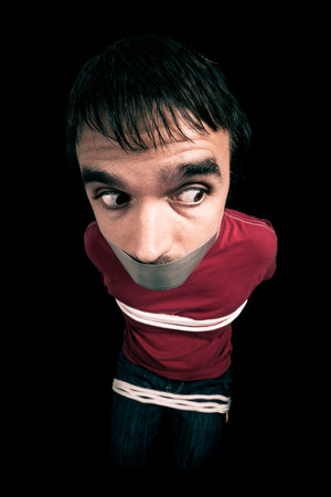 Kidnapped man hostage with tape over mouth and tied up with ropeの写真素材