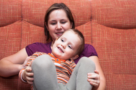Happy child boy and mother on sofaの写真素材