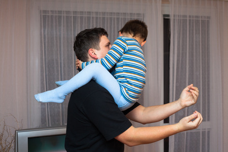 Happy father playing with his child boy at homeの写真素材