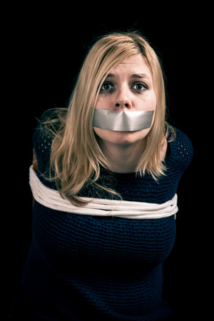 Kidnapped woman hostage with tape over mouth and tied up with ropeの写真素材