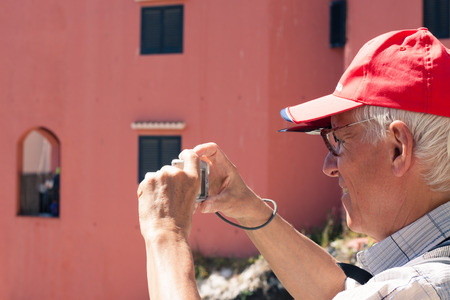 Senior man tourist taking photos using compact camera.の写真素材
