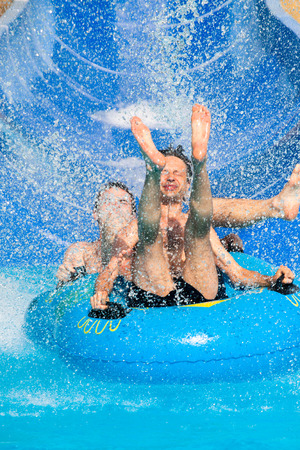 Two men having fun, people water slide at aqua park.の写真素材