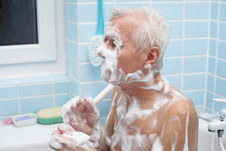 Senior man washing his body with soap in bath.の写真素材