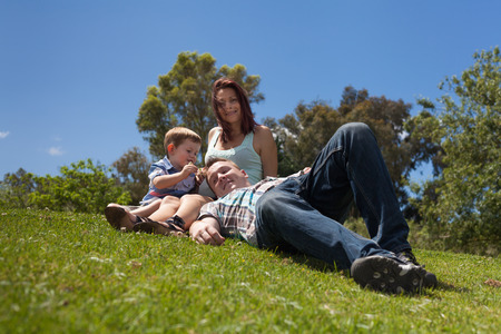 Young happy family relaxing in the grass and enjoying summer day outdoors.の写真素材