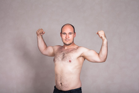 Portrait of shirtless man posing and showing his strong arms and hairy body.の写真素材