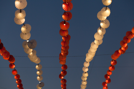 Red and white lights and decorations over blue evening sky in the amusement park.の写真素材
