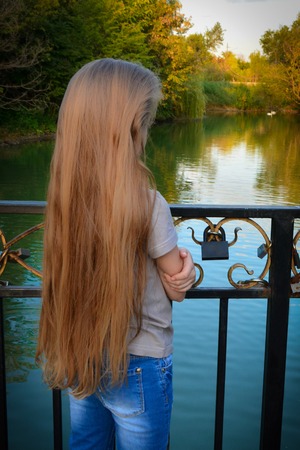 girl with long hair on a bridge by the riverの写真素材