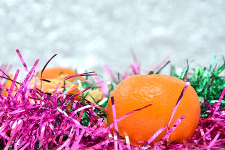 Christmas tree toys on red napkin. Mandarins and candles on the table. A fur-tree branch and fruit on a New Years table.の写真素材