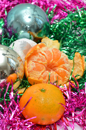 Christmas tree toys on red napkin. Mandarins and candles on the table. A fur-tree branch and fruit on a New Years table.の写真素材