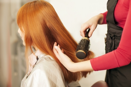 Beautiful young hairdresser giving a new haircut to female customer at parlorの写真素材